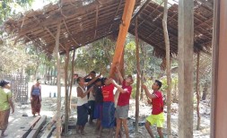 Workers stand up a main support beam at the new house being built for ministry workers